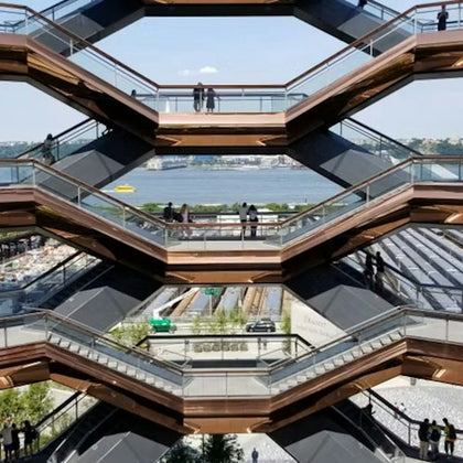 Multi-level structure with people walking on various platforms, overlooking a river and a construction site below.