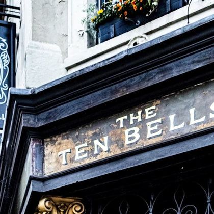 A sign reading 'The Ten Bells' above a doorway, with a flower box and ornate architectural details visible.