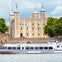 A boat named 'Thomas Doggett' on a river with the Tower of London in the background on a sunny day.