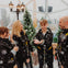 A family in winter gear stands inside a dome with fake snow and Christmas trees, smiling and enjoying the scene.