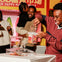 A group of people enjoying a candy store. A person is filling a container with candy, while others smile in the background.