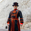 A man in traditional black and red uniform stands in front of a stone wall. His attire features a crown symbol and "ER" lettering.