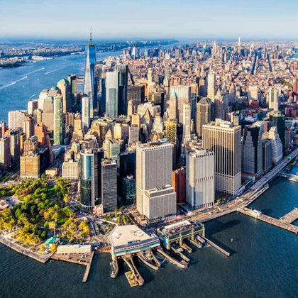 Aerial view of a cityscape featuring tall skyscrapers, green park areas, and surrounding waterways.