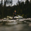 Person riding a jet ski on a body of water with a dense forest in the background.