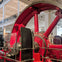 Large red industrial machinery with gears and pipes, displayed in a spacious museum setting.