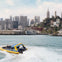 A yellow boat labeled "Rocketboat" filled with passengers on water, with a "Pier 39" flag waving in the foreground.