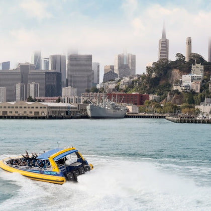 A yellow boat labeled "Rocketboat" filled with passengers on water, with a "Pier 39" flag waving in the foreground.