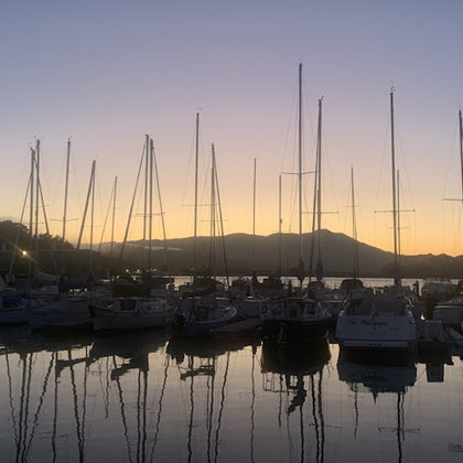 The sun is setting on a calm evening at the marina.