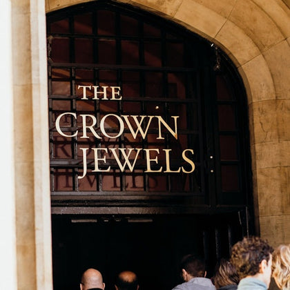 People entering an arched doorway with a sign that reads "The Crown Jewels."