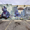 A mural depicting a rhinoceros in a suit and a bird flying near colorful flowers against a background of buildings.