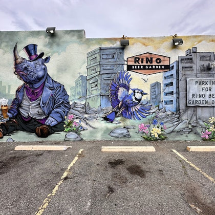 A mural depicting a rhinoceros in a suit and a bird flying near colorful flowers against a background of buildings.