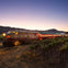 A vintage train labeled "Napa Valley" travels through a vineyard at dusk, with a mountain silhouette in the background.