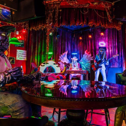 A colorful stage setup with mannequins dressed as angels and musicians standing under vibrant lighting in a decorated room.