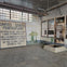An interior view of a room with a sign reading "United States Penitentiary" and weathered walls and barred windows.