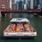 A sightseeing boat named 'Skyview' filled with people cruising on a river through a city with tall buildings and a bridge.