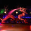 Illuminated dragon statue spouting water at night, surrounded by colorful lights and lanterns against a dark background.