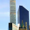 A cityscape featuring modern skyscrapers and a historic building with ornate architectural details under a clear sky.