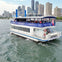 A sightseeing boat named 'Showboat Royal Grace' on a body of water, with a city skyline and tall buildings in the background.