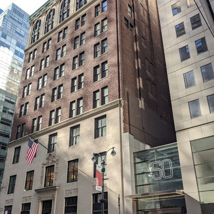 A brick building with an American flag, adjacent modern glass and stone buildings, and a sign showing the number 350.