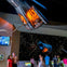 Visitors in a museum observe hanging spacecraft capsules with illuminated interiors against a starry backdrop.