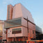 Modern building with angular design and large glass windows. Traffic lights and "No Turn" signs visible in the foreground.