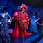 Three elaborate costumes on mannequins: a red skeleton in the center, flanked by two Victorian-style dresses, against a dark, draped background.