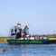 Tourists seated on an airboat in a marshland, with a captain at the helm and tall grasses in the background.