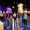 A group of people stand near a Warner Bros. Studios water tower exhibit in a museum-like setting with displays in the background.