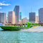 Green speedboat labeled "Hurricane" speeding through water, with city skyscrapers in the background.
