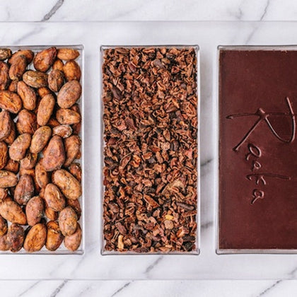 Three sections display cocoa beans, cocoa nibs, and a chocolate bar with the word 'Raaka' embossed, on a marble surface.