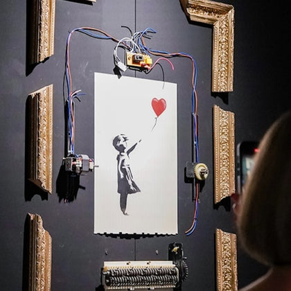 A shredded artwork depicting a girl with a red balloon, surrounded by a dismantled frame and wires, with a viewer observing.