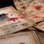 Old documents and letters with handwritten text and stamps, some stained with red marks, arranged on a surface.