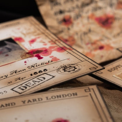 Old documents and letters with handwritten text and stamps, some stained with red marks, arranged on a surface.