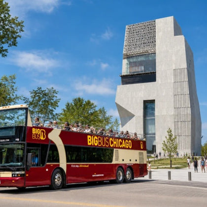 A red double-decker tour bus labeled "Big Bus Chicago" parked near a modern building with geometric architecture.