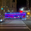 Open top double decker tour bus passing the Fairmont Royal York Hotel at night. Outline of bus is covered in LED lights