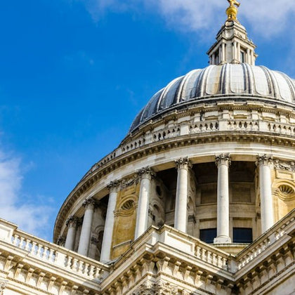 Close-up view of a domed building with classical architecture against a blue sky.