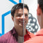 A person in a red shirt is looking into a mirror, with their reflection visible. Geometric designs are in the background.