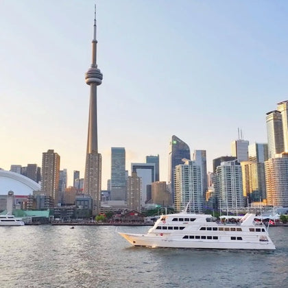 A city skyline featuring a tall tower and modern buildings, with a white boat on a body of water in the foreground.