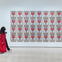 Person in a red coat walks past a wall display of framed Campbell's Soup can artworks arranged in a grid.