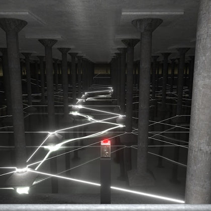 A dimly lit room with many columns and glowing light beams crisscrossing the space, connected to a central pillar with a red light.