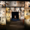 A museum exhibit with walls covered in Titanic newspaper headlines, featuring a spotlighted chair in the background.