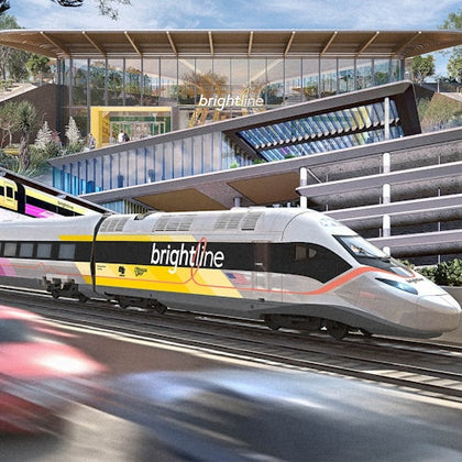 A bright yellow and white high-speed train labeled 'Brightline' passing in front of a modern station building with large windows.