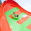 Two people ride a green inflatable tube down a brightly colored orange and green water slide with splashing water.