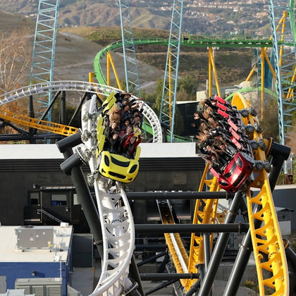 Three people screaming on a roller coaster ride with green safety bars, showing excitement and thrill.