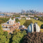 Aerial view of historical buildings and observatories with domes surrounded by green parks, set against a modern city skyline.