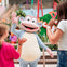 A person in a cartoon monkey costume high-fiving two children in a colorful indoor play area.