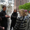 A group of people having a discussion in an outdoor urban setting with modern art sculptures and trees in the background.