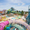 A vibrant water park featuring colorful slides, pools, and visitors enjoying the attractions under a sunny sky.