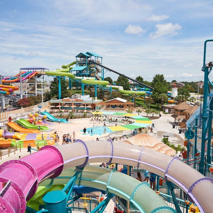 A vibrant water park featuring colorful slides, pools, and visitors enjoying the attractions under a sunny sky.