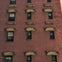 A brick building facade with multiple windows, each having decorative stone accents above them.